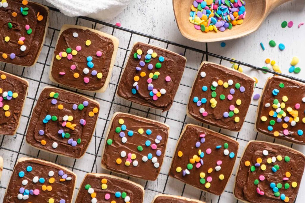 Square frosted cookies with sprinkles on top.