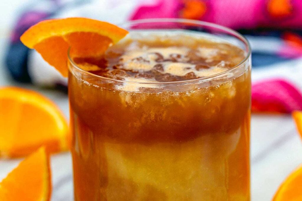 Coffee and ornage juice in a glass cup.