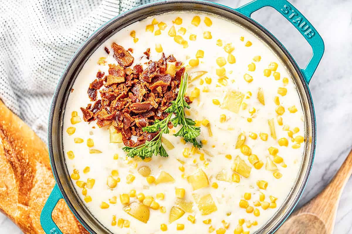 Corn Chowder in a blue pot with bacon on top.
