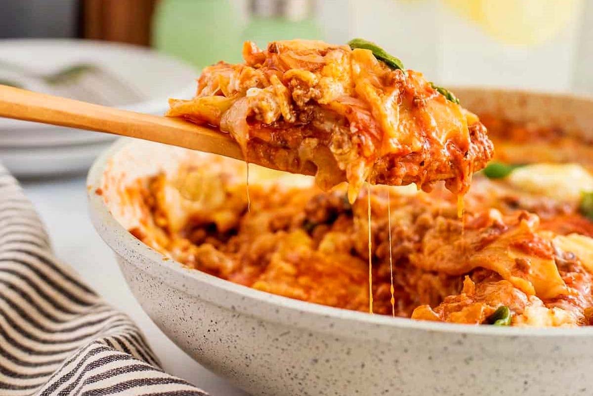 Scooping lasagna out of a skillet.
