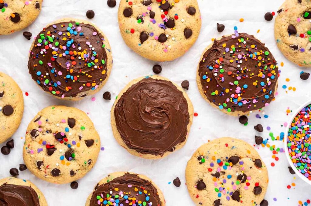 Frosted chocolate chip cookies with rainbow sprinkles on top.