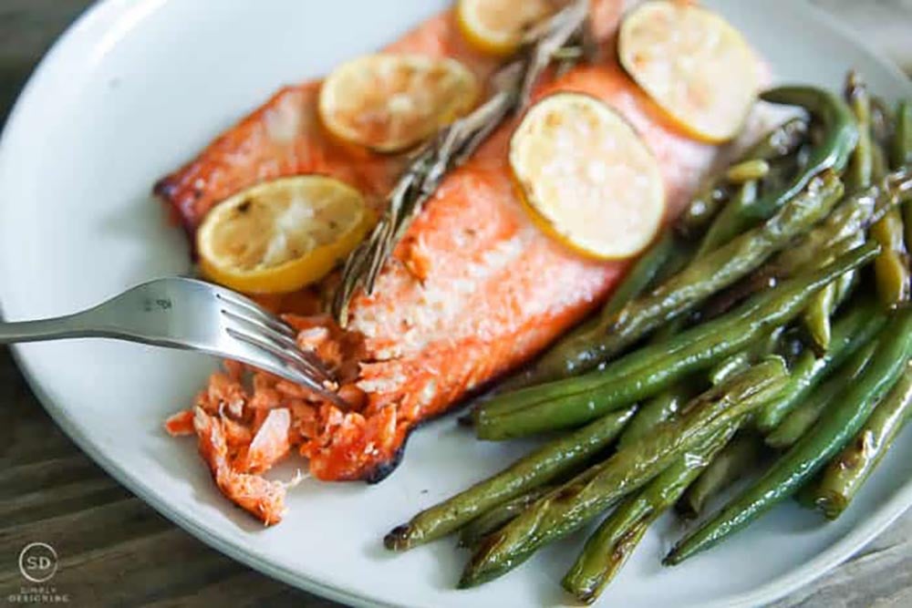 Honey lemon grilled salmon served on a plate with lemons and green beans