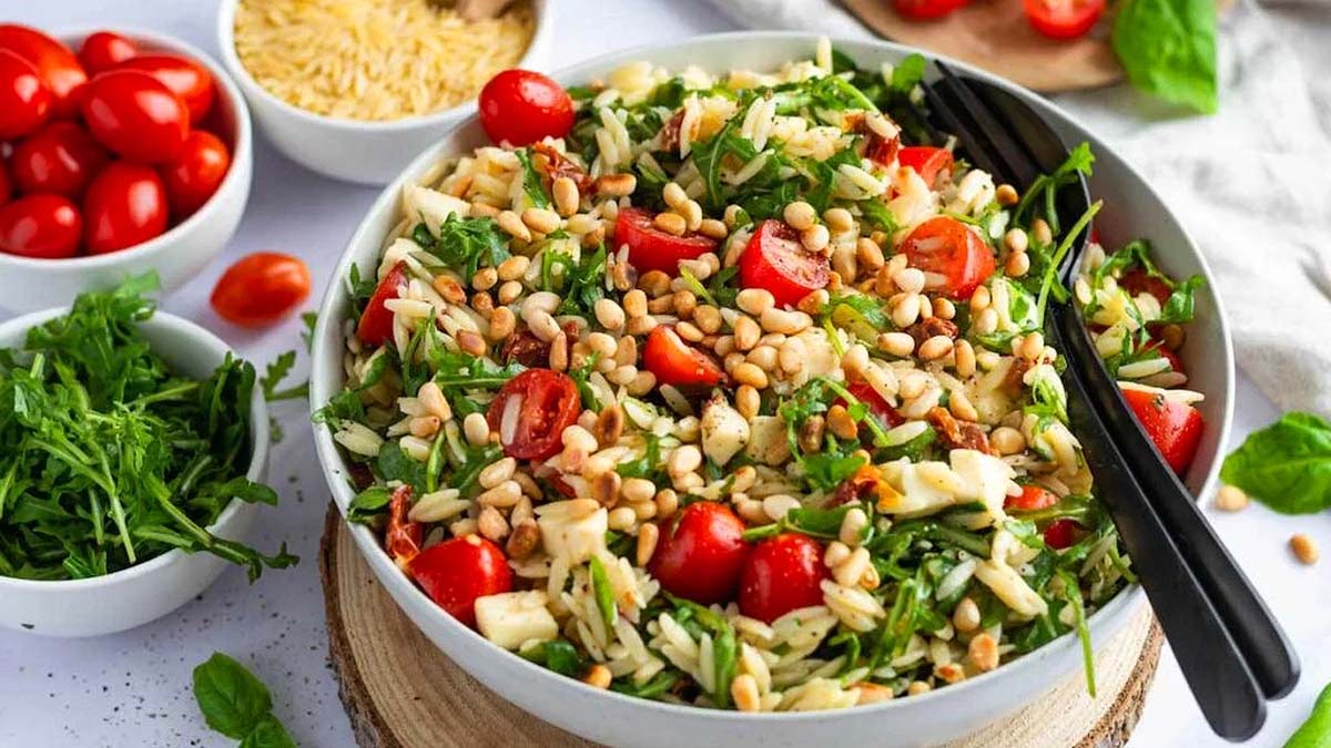 Orzo salad with beans and tomatoes in a bowl with a fork