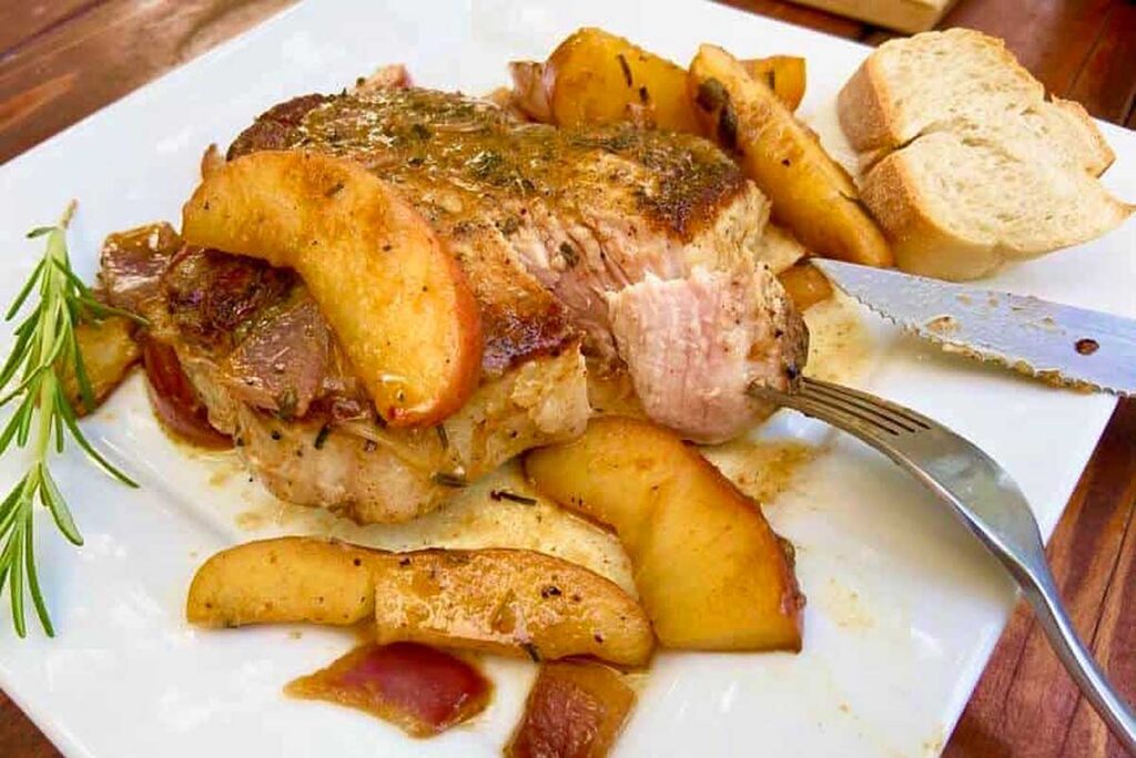 Pork chop with fried apples served on a white plate