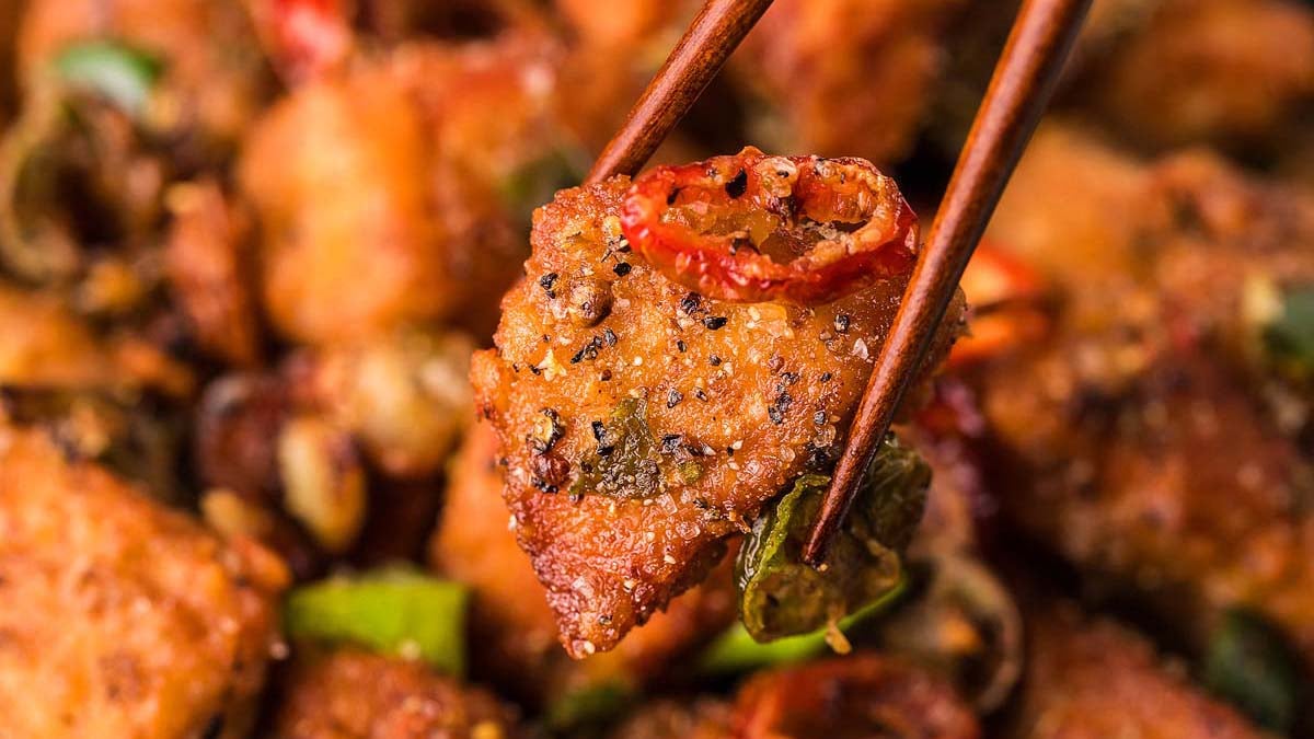 A pork chop bite with chopsticks.