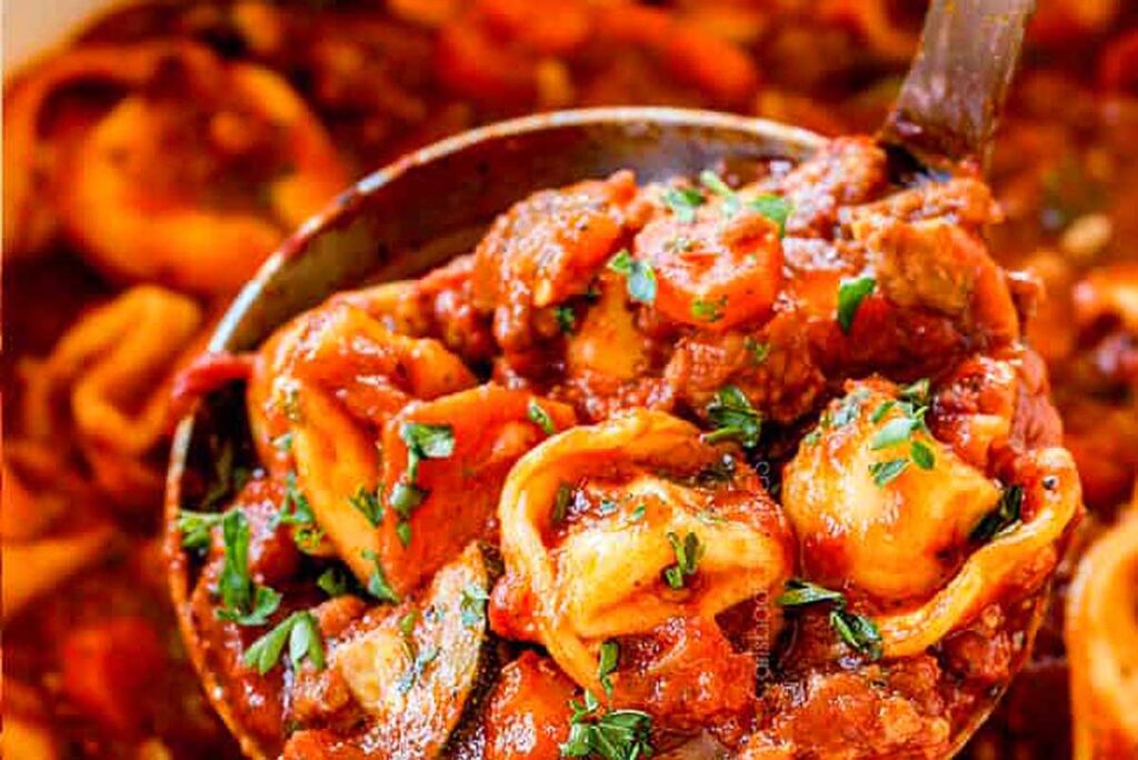 Sausage Tortellini Soup being scooped out of a pot.