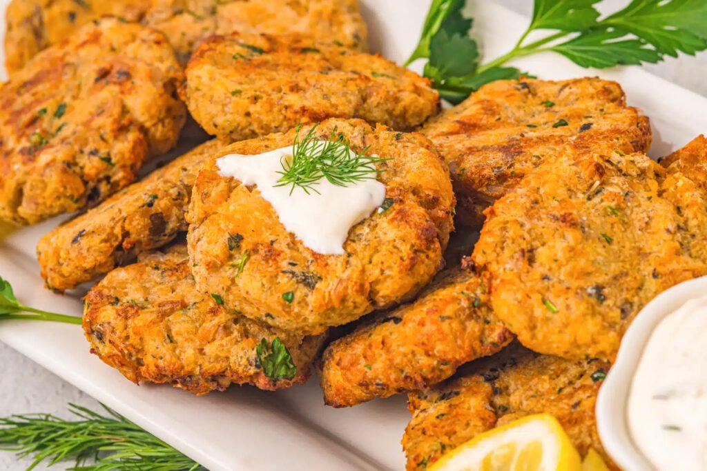 Salmon patties on a platter with dip.