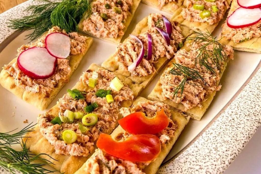 Salmon salad on flatbread with fresh vegetable toppings.