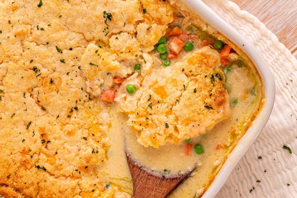 Scooping chicken cobbler from a pan.