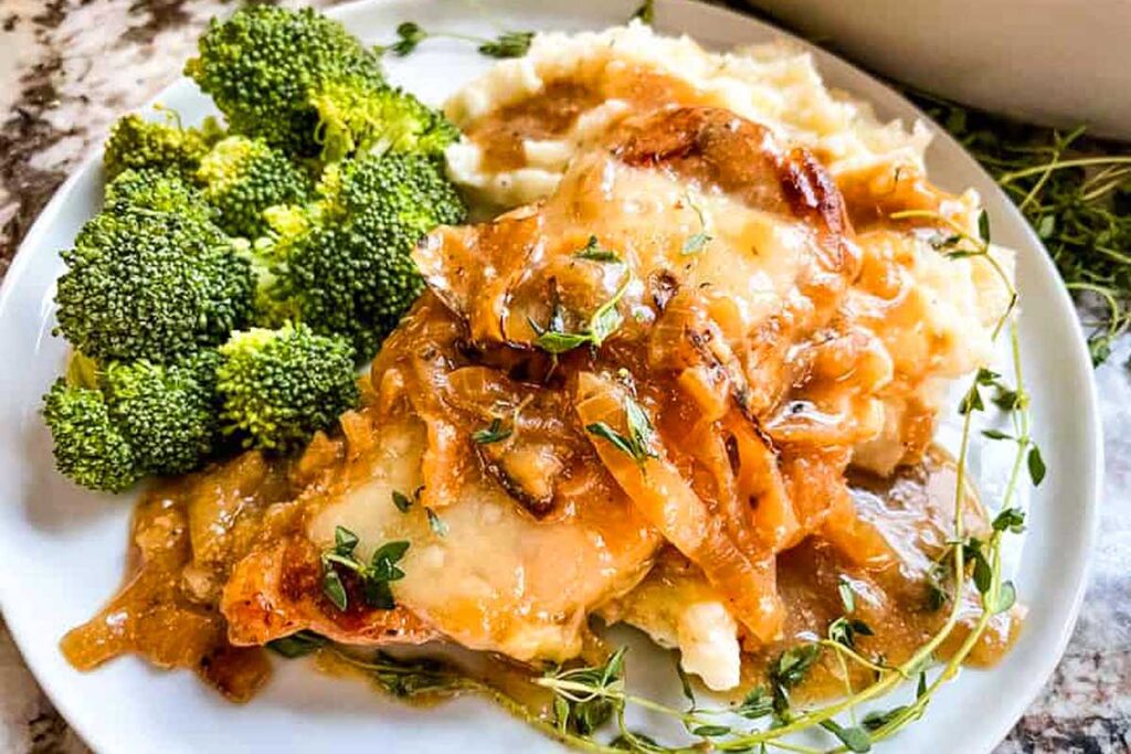 Pork chops piled high with cooked onions and melty cheese