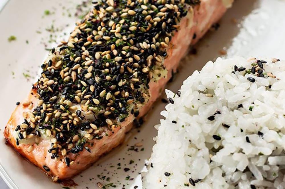 Furikake seasoning spread onto baked salmon filets served with rice.
