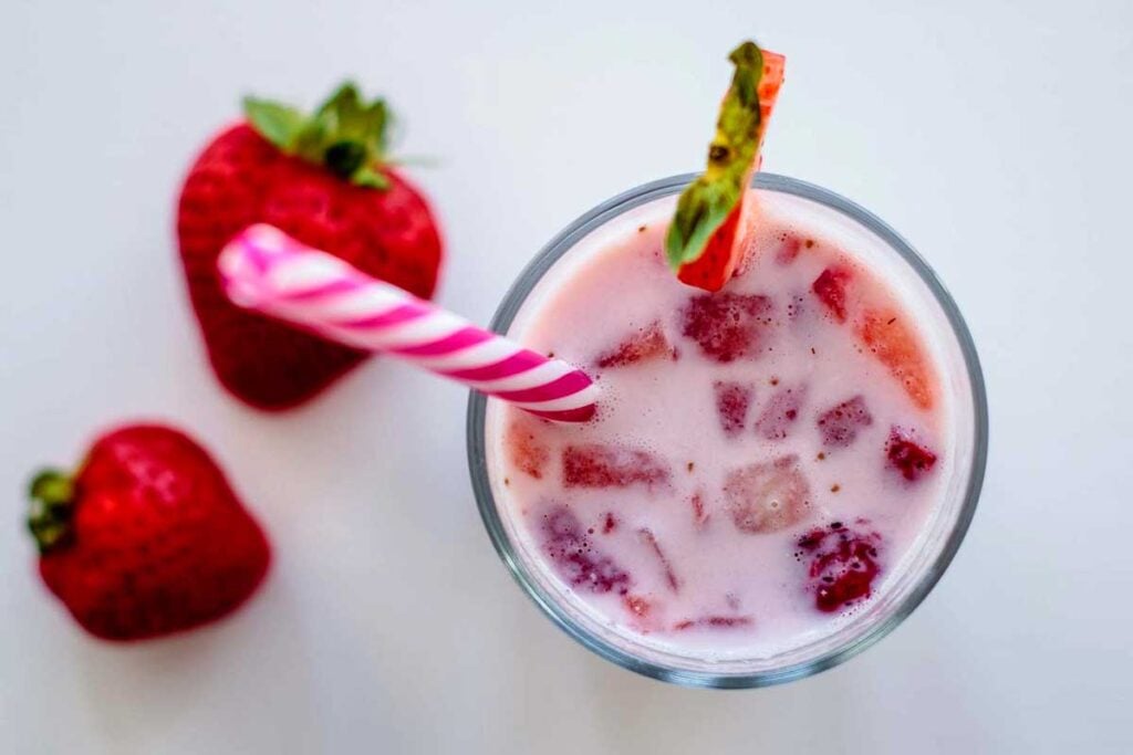 Overhead shot of Korean strawberry milk with chunks of strawberries in a glass with a straw