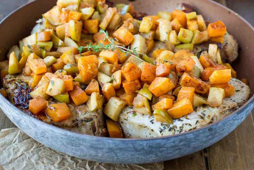 Pork chops with apples and butternut squash in a skillet
