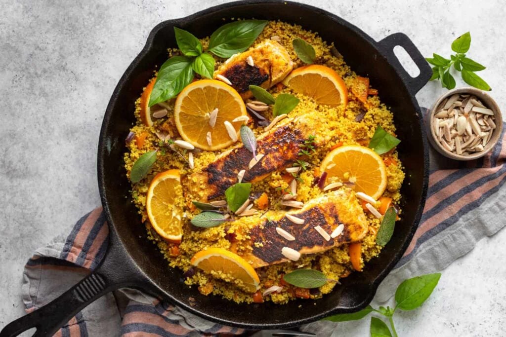 A cast iron skillet with a salmon dish in it.