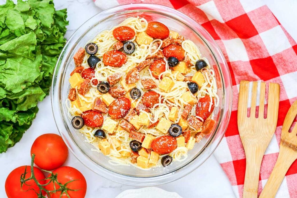 a bowl of spaghetti noodles with cheese, pepperoni and olives