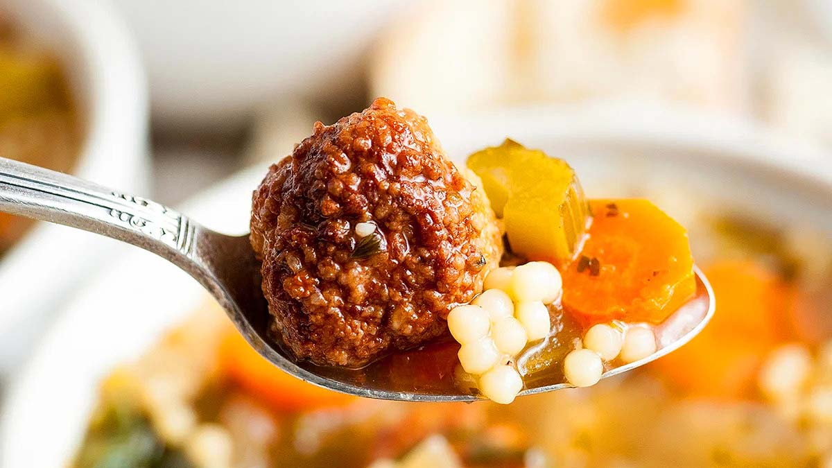 A spoon taking a scoop out of a homemade Italian wedding soup.