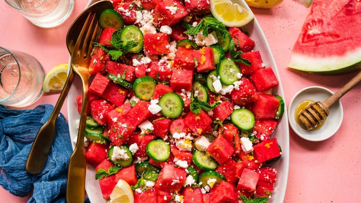Overhead view of a watermelon feta cucumber salad on a large platter.