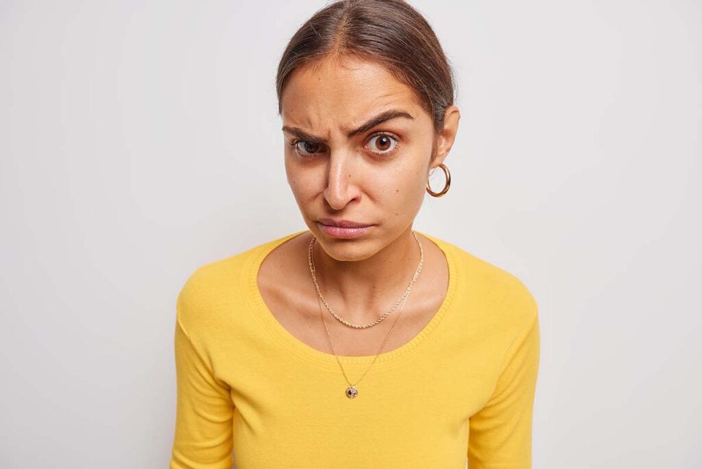 Serious woman raises eyebrows looks skeptical.