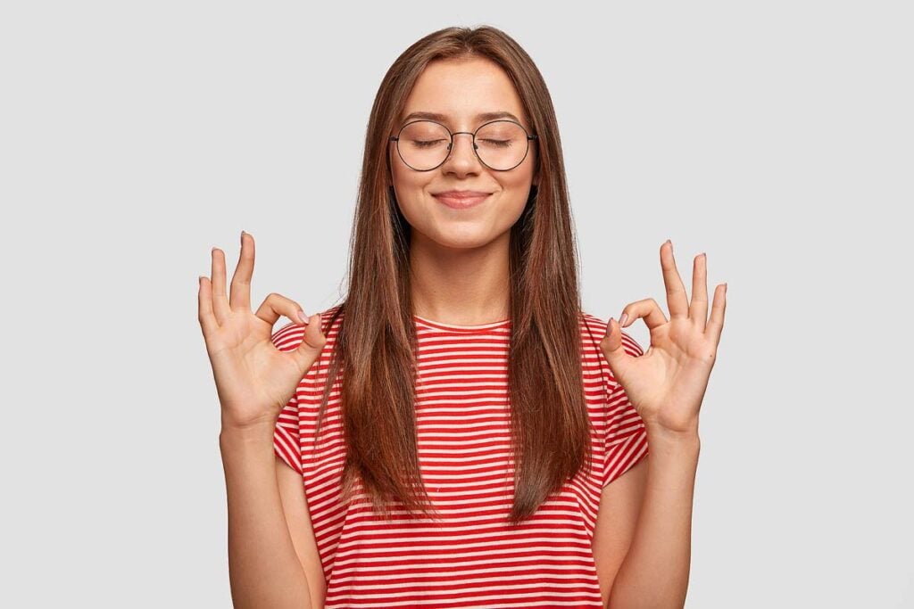 Pleased satisfied young female model makes zero gesture.