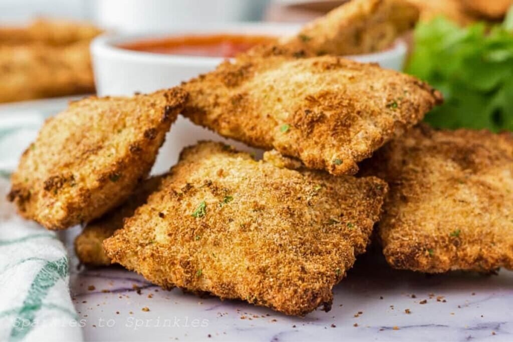 Crunchy fried ravioli with marinara sauce in a bowl.