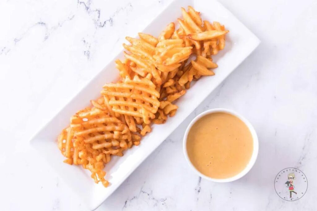 Chick fil a sauce in a cup with waffle fries on a plate.