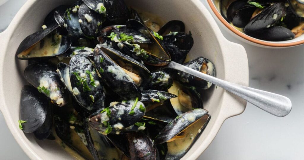 A bowl of cream sauce with mussels.