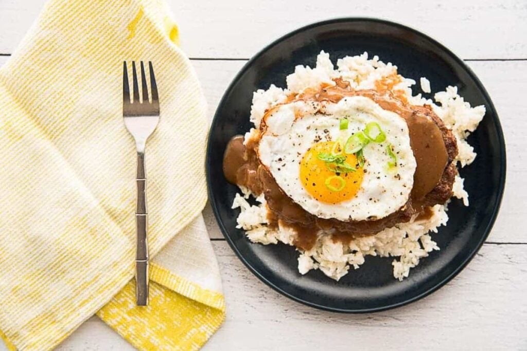 A beef patty topped with an egg and gravy.