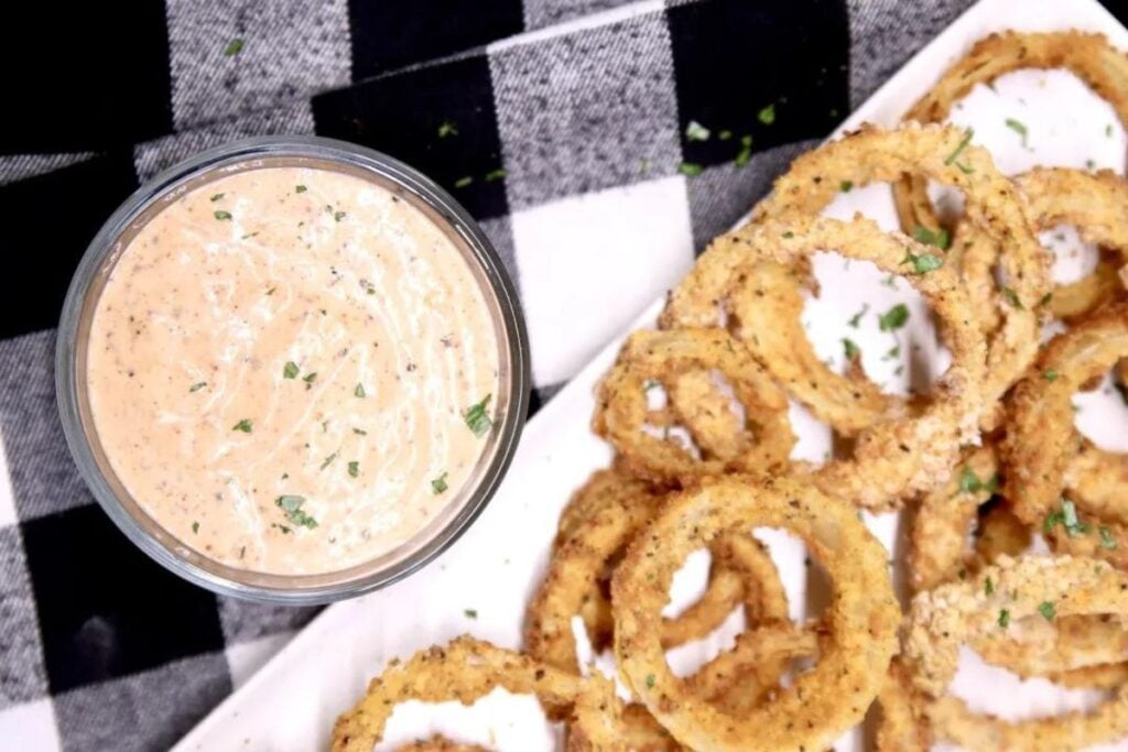 A dish of onion sauce with onion rings on the side.