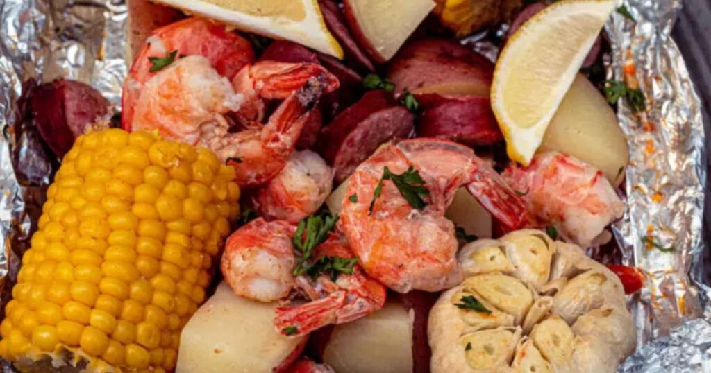 A foil pack with shrimp, corn, potatoes.