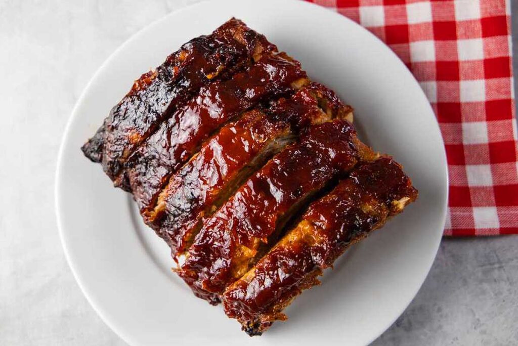 A rack of baked ribs with plenty of sauce.