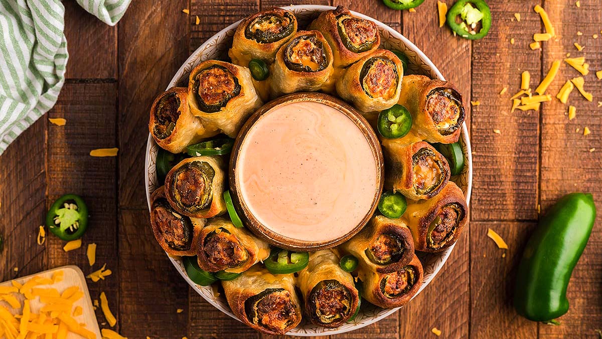 Jalapeno popper rolls on a plate with a bowl of dip.