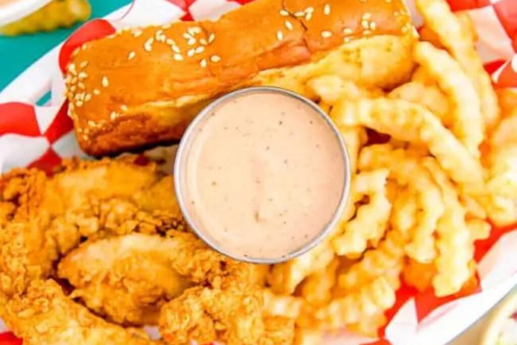 A small dish of cane's sauce with fries, bread and chicken.