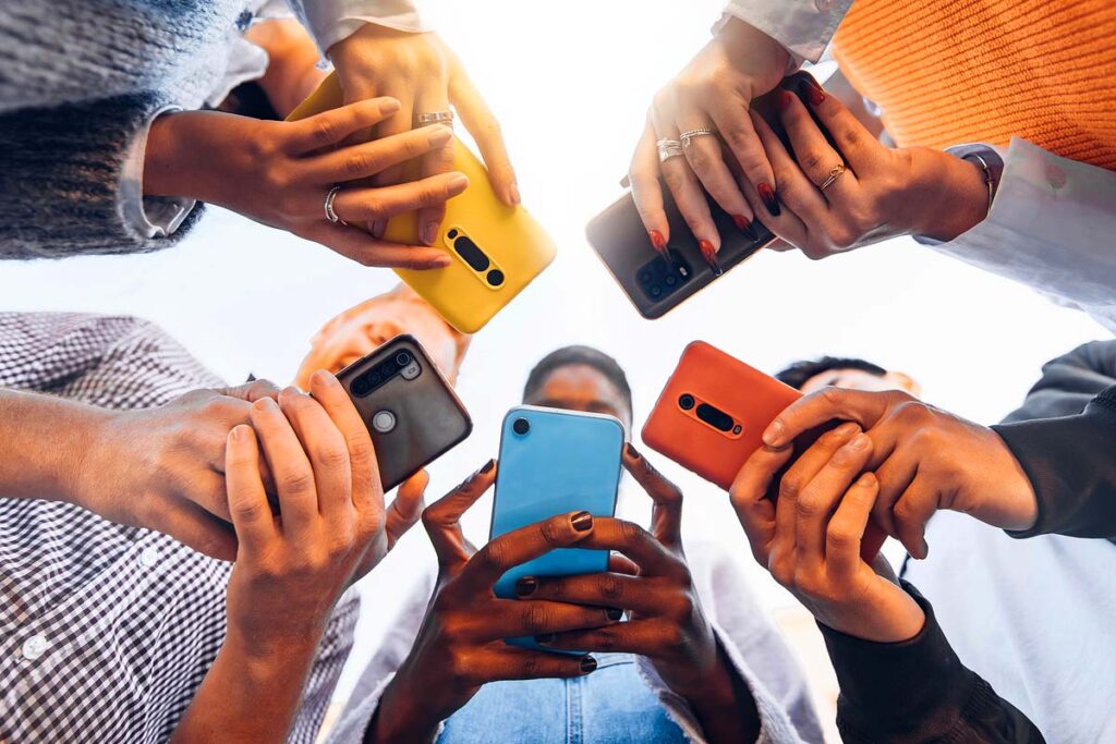 Teens in circle holding smart mobile phones.