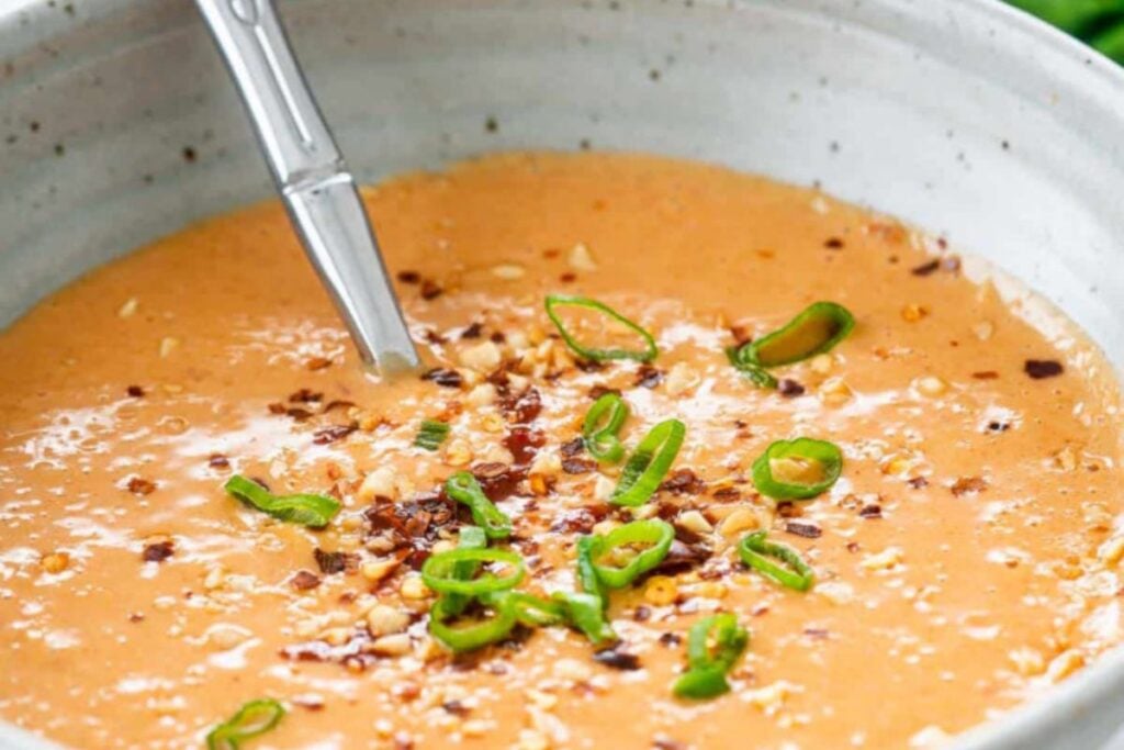 A bowl of peanut sauce with seasonings.