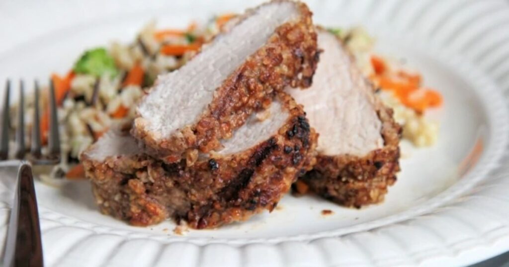 Slices of pecan crusted pork tenderloin on a plate.