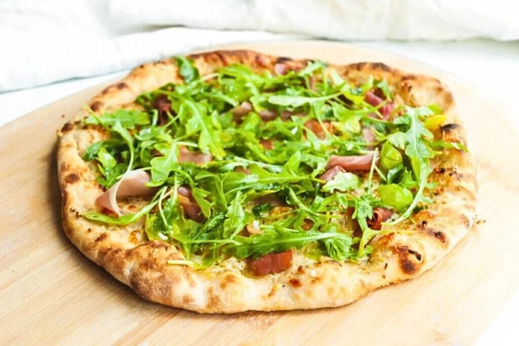 A pizza topped with prosciutto and arugula.