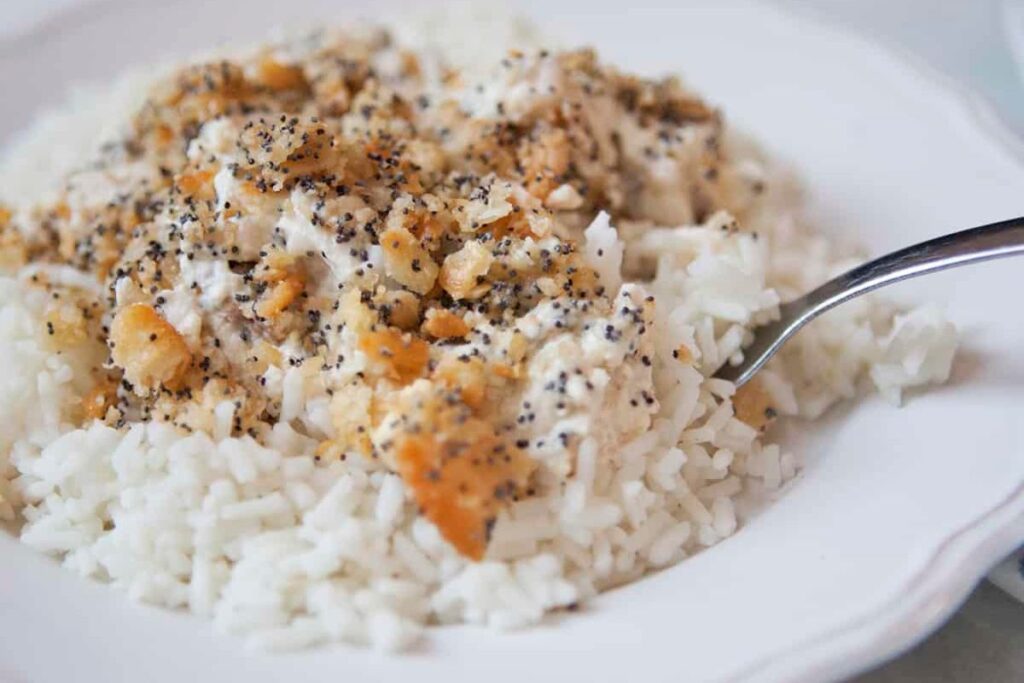 Poppy seed and cracker crumb coated chicken casserole in a white bowl.