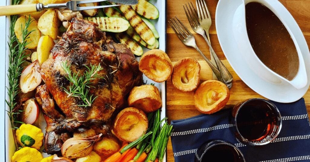 A leg of lamb with roasted veggies on a platter.
