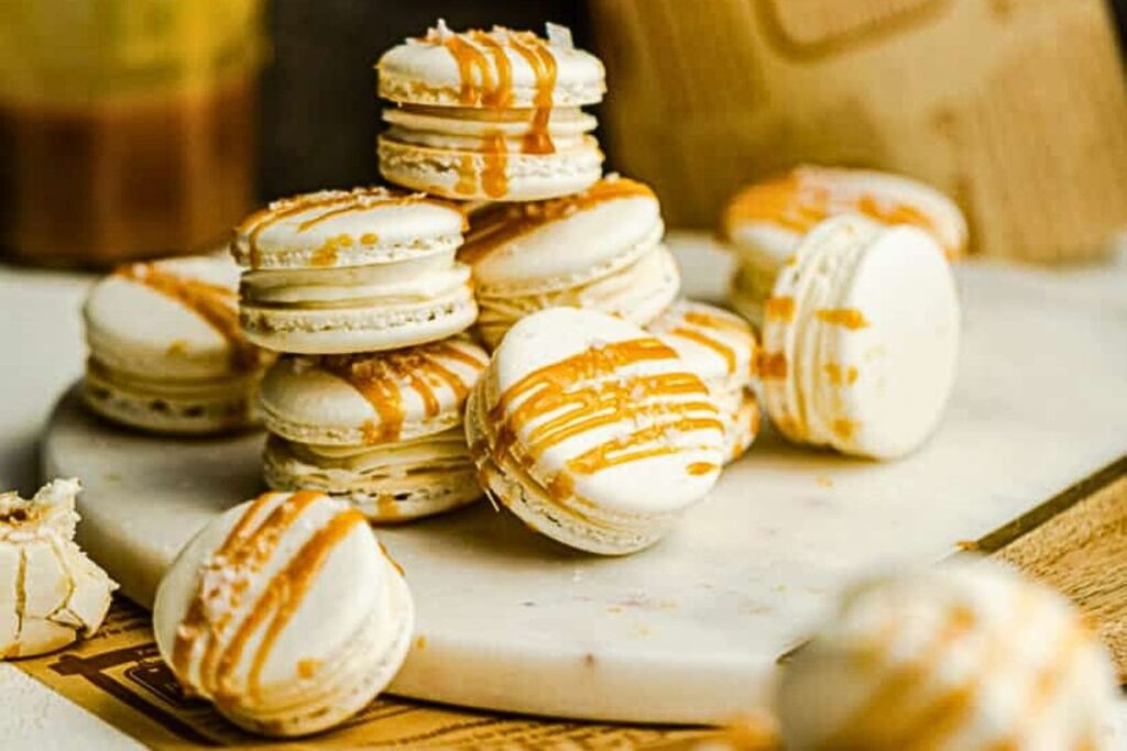 Salted caramel macarons in a pile on a plate.