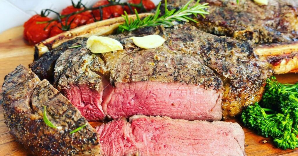 A tomahawk steak grilled. Laying on a wooden platter.