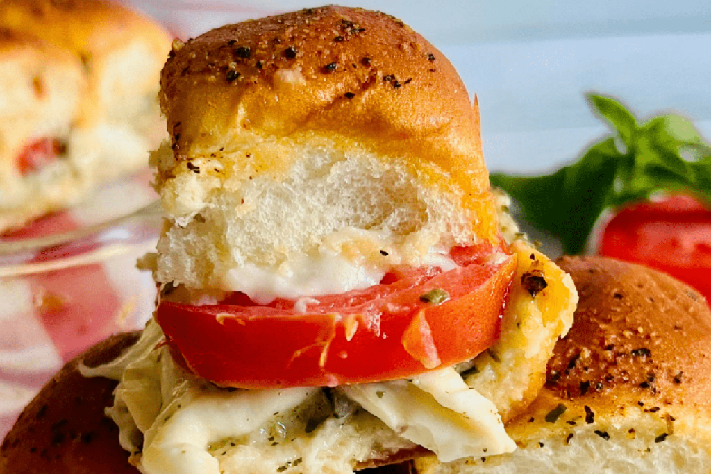A baking dish of basil, tomato and mozzarella slider sandwiches.