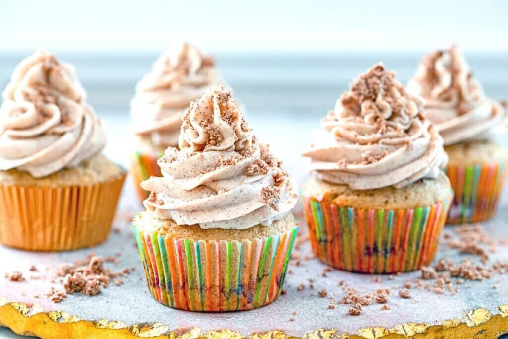 Coffee cake cupcakes piled high with fluffy frosting.