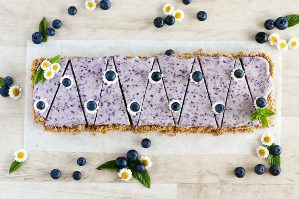 A plate of blueberry cheesecake sliced into triangles.