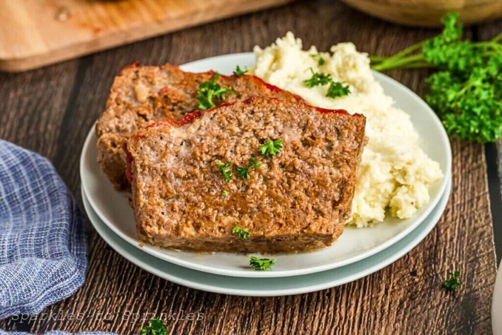 A slice of lipton onion soup mix meatloaf on a plate with mashed potatoes.