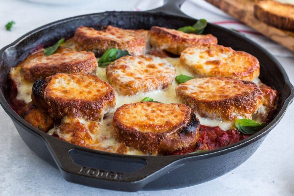 Crusty bread baked on top of tomato sauce, cheese and chicken meatballs in a large skillet.