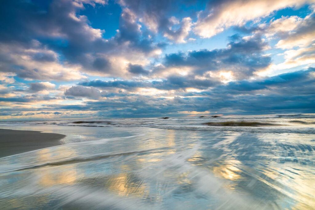 Beautiful sunrise on Hunting Island State Park beach with waves crashing on the sand.