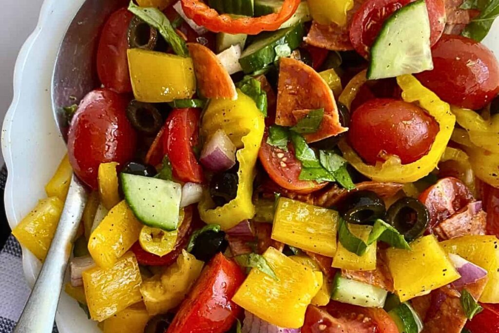 A bowl of chopped salad with tomatoes, onions, cucumbers and peppers.