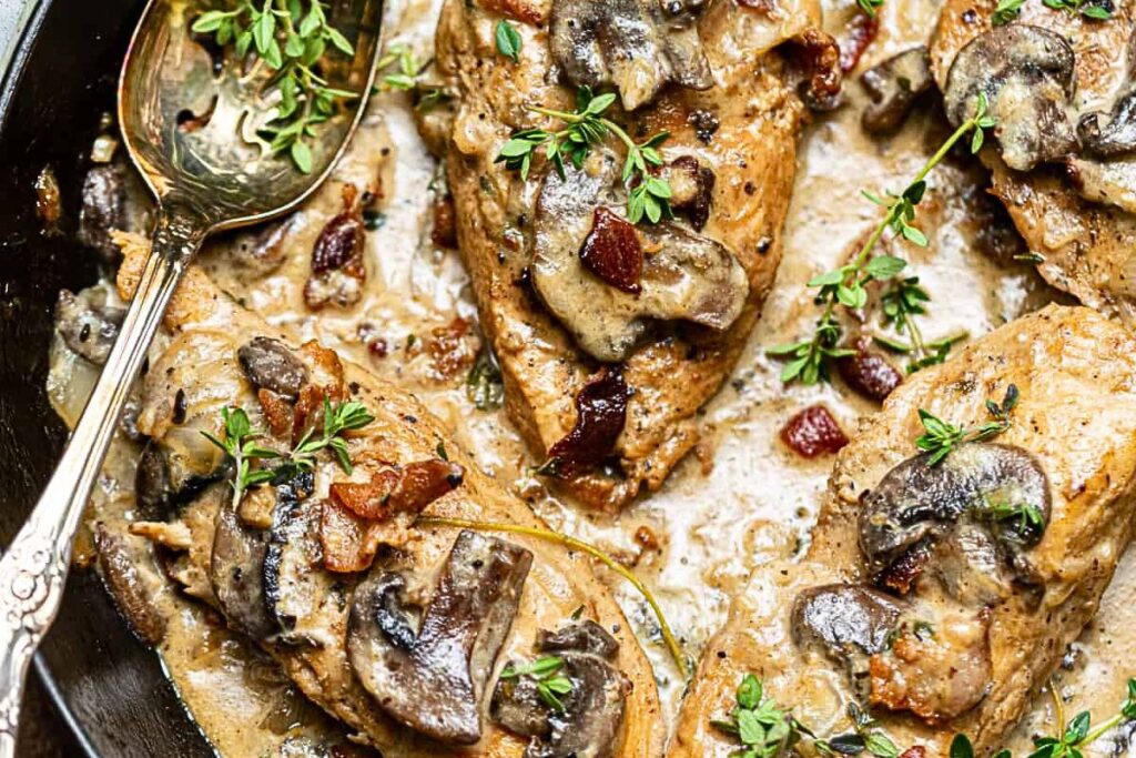 Chicken in a skillet with creamy sauce and mushrooms.