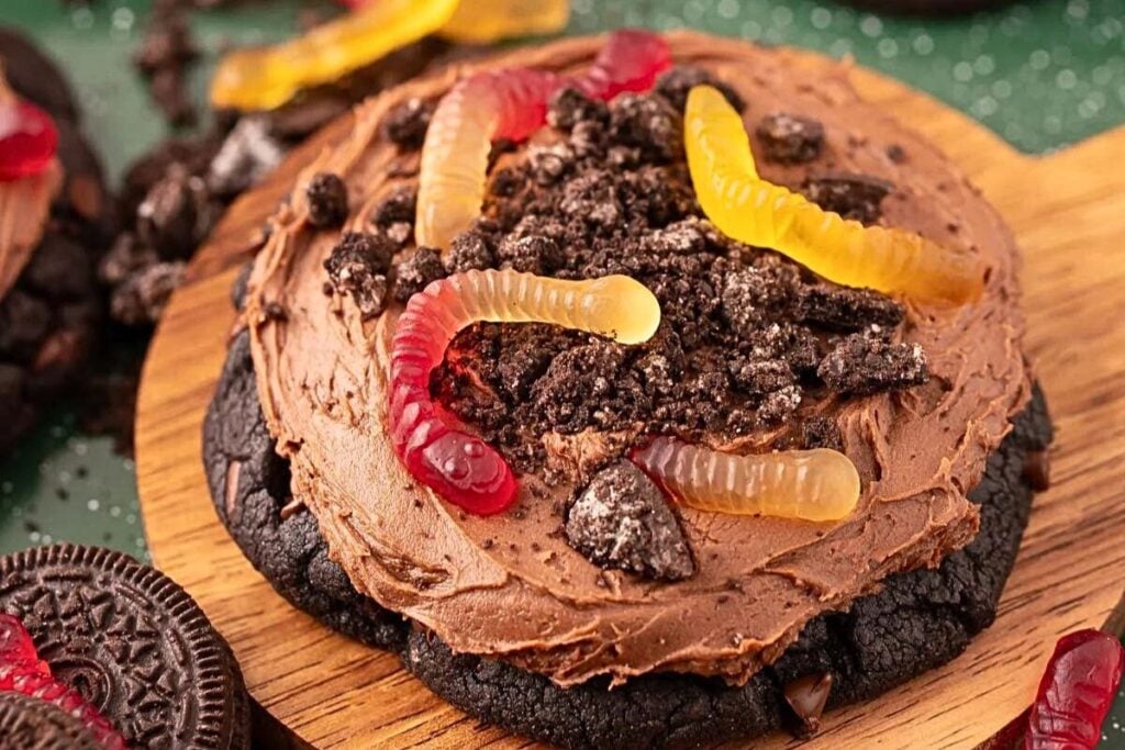 Chocolate cookie, with frosting, cookie crumbs and gummy worms.