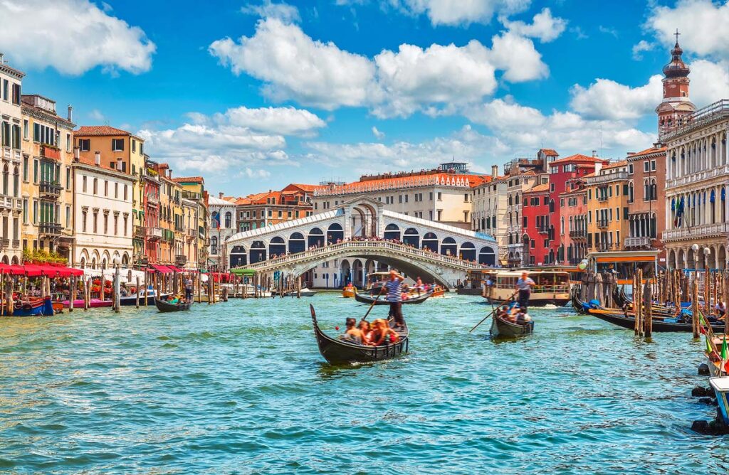 Bridge Rialto on Grand canal famous landmark panoramic view Venice Italy with blue sky white cloud and gondola boat water.